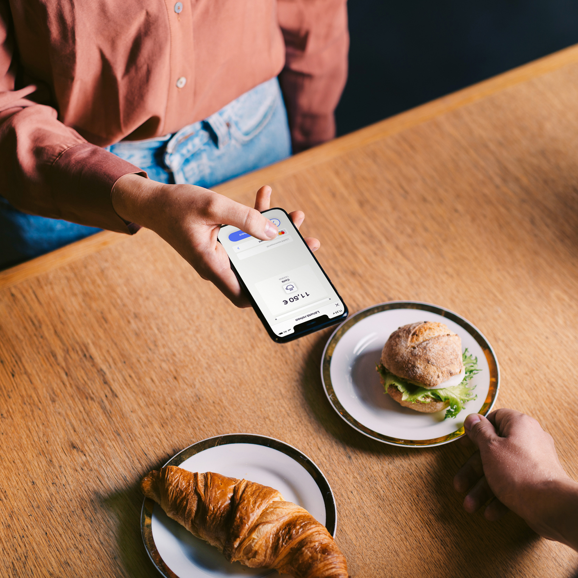 Nainen maksaa välipalan MobilePay sovelluksella kahvilassa