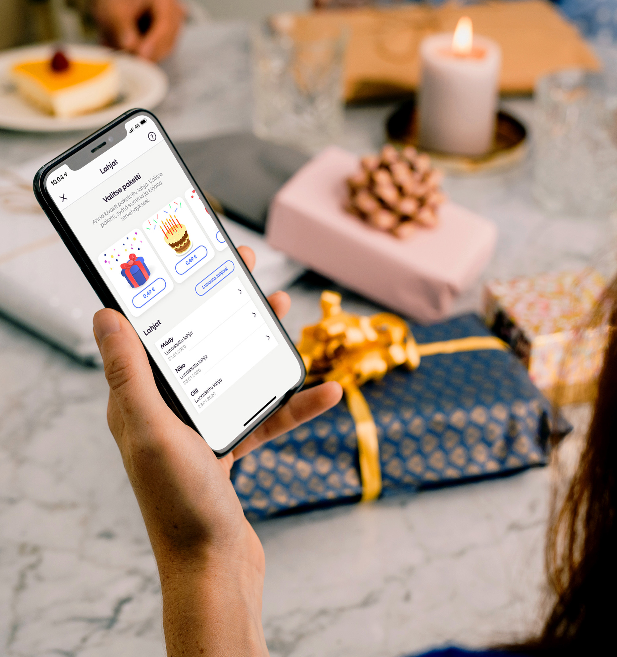 Henkilöllä puhelin kädessä lahjapöydän ääressä, MobilePay sovellus auki rahaa lahjaksi näkymässä