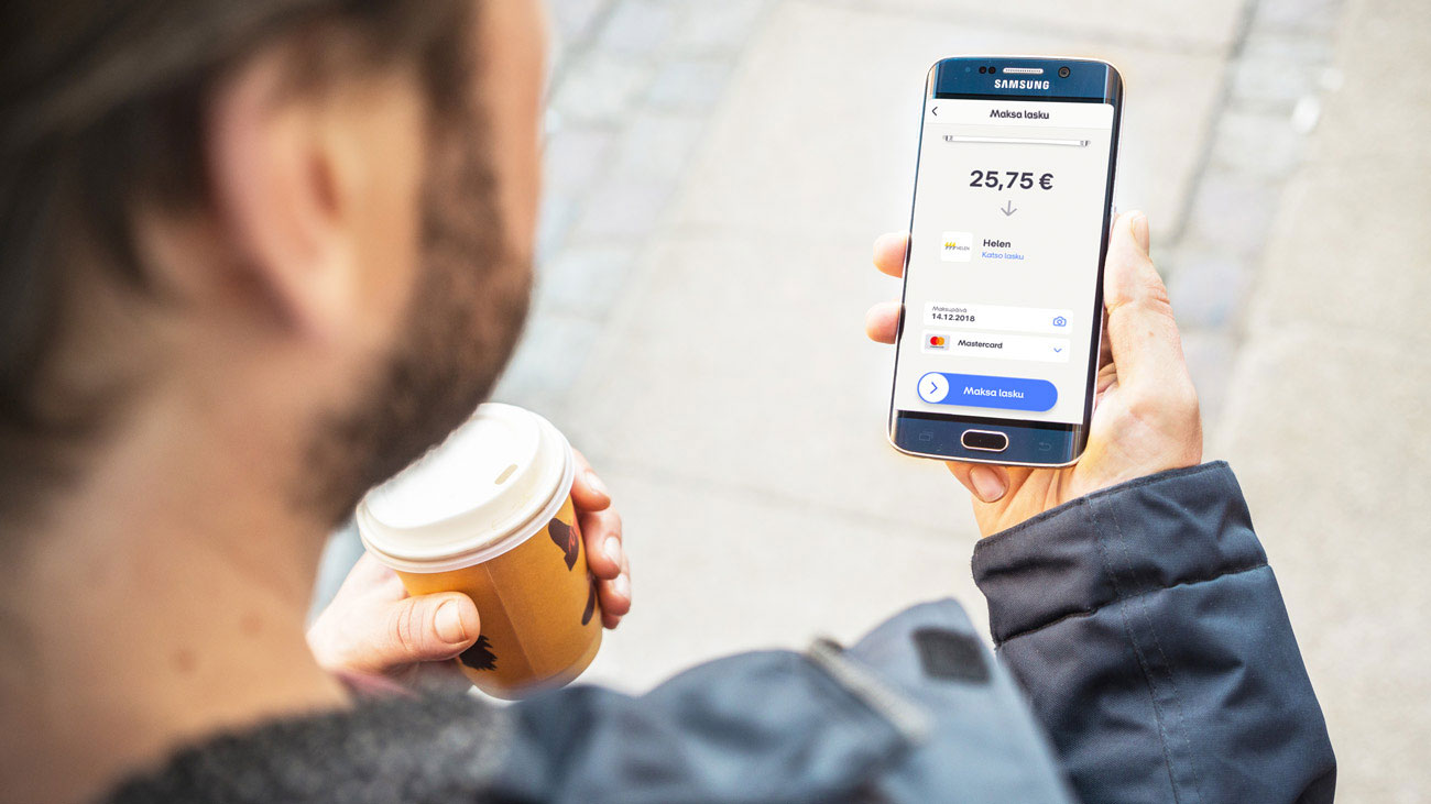 Mies puhelimella hyväksymässä Helenin laskua MobilePay sovelluksessa